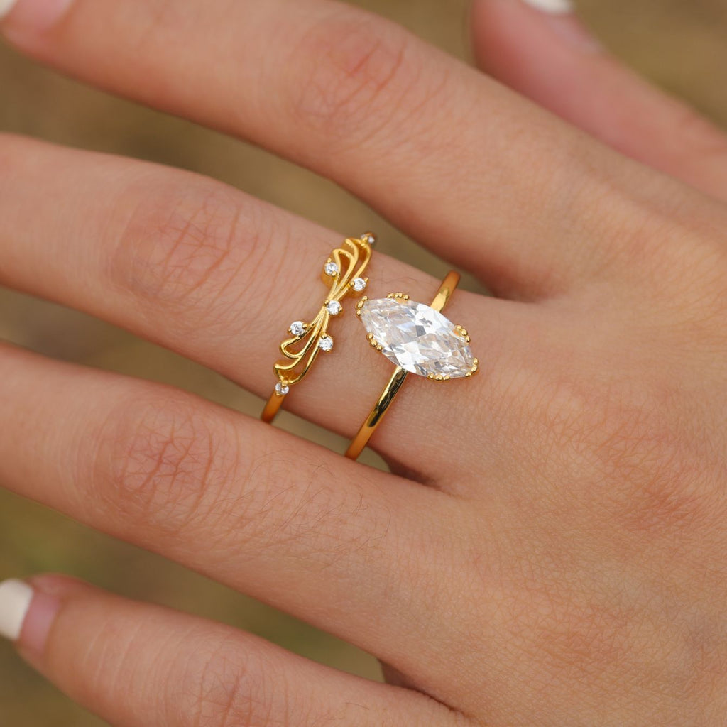 Gold-plated moissanite ring set with marquise solitaire and vine-inspired accent ring in a hand